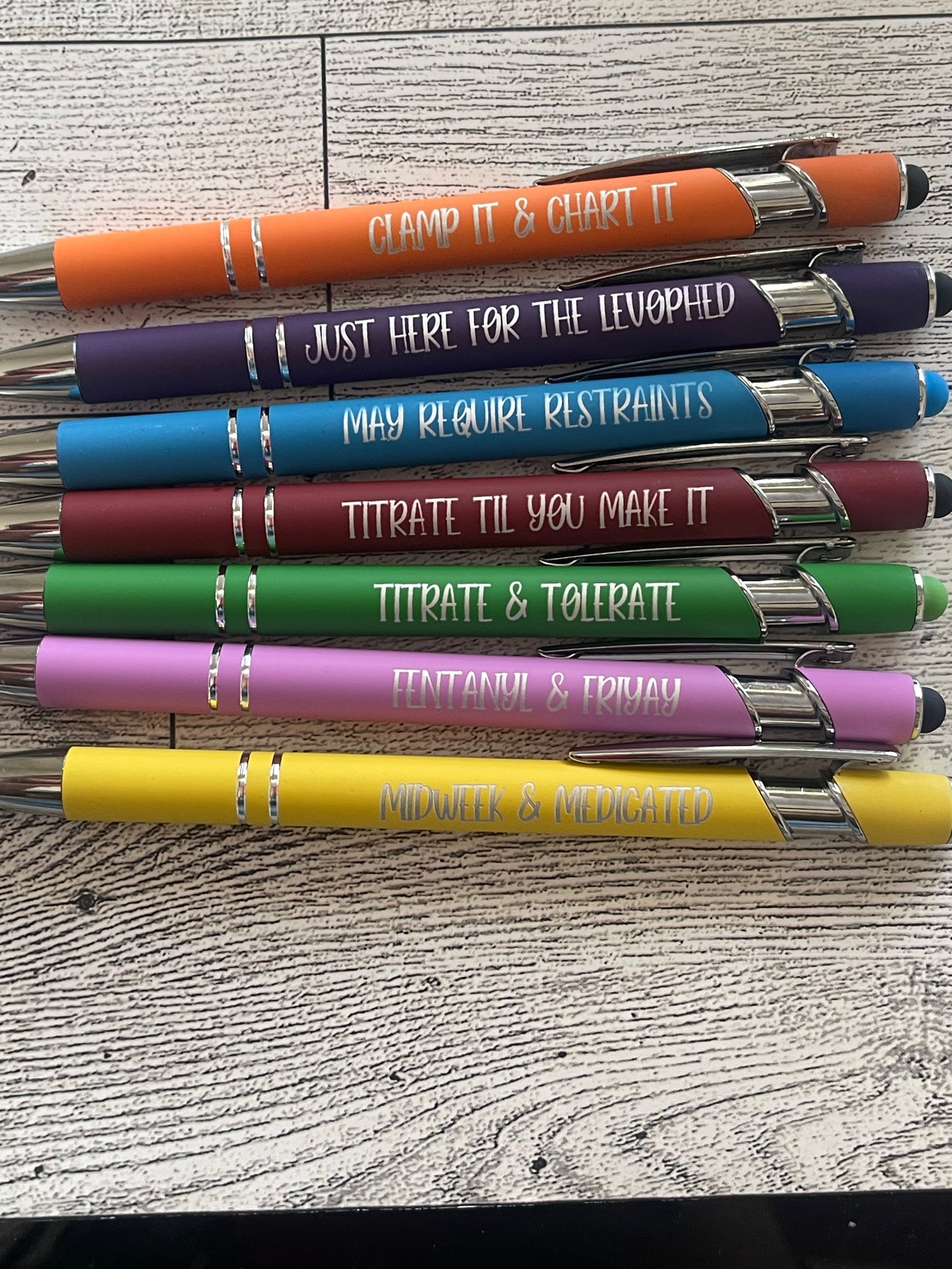 Set of colorful pens with engraved text about icu nurse on a textured surface