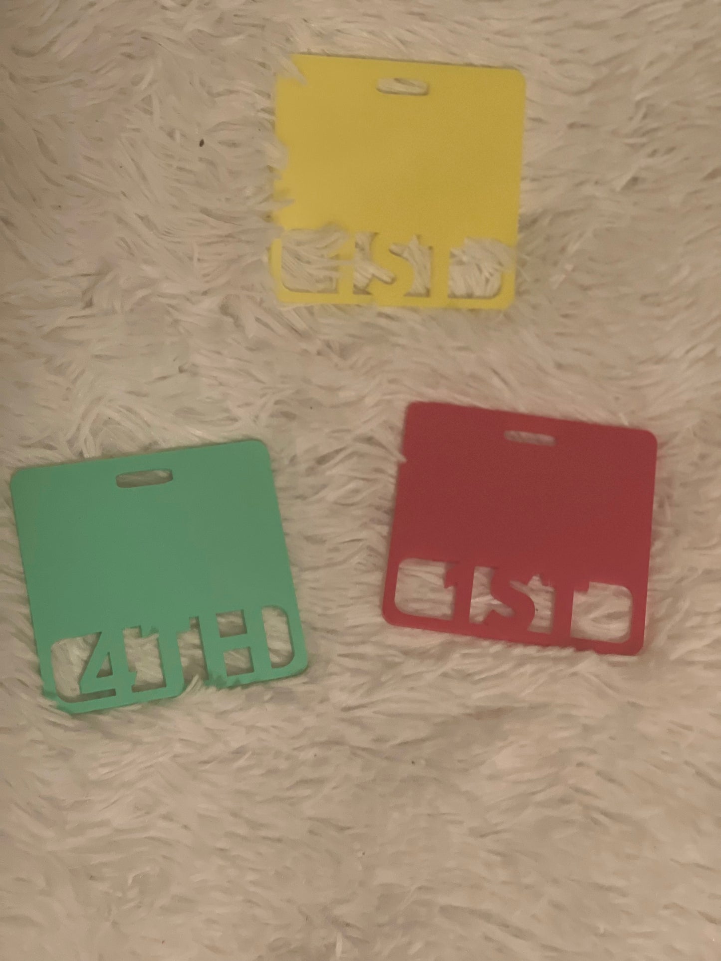 Three acrylic name plates in yellow, green, and red, designed in a badge style with cut-out words.