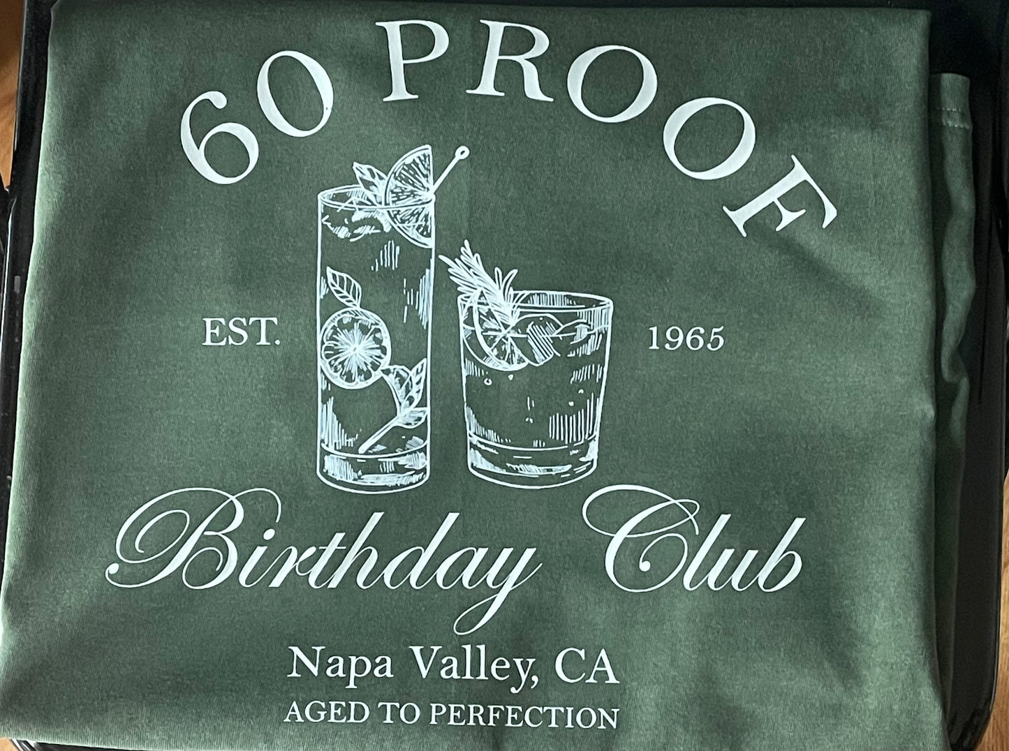 Green shirt with '60 Proof Birthday Club' design featuring cocktail graphics and text.