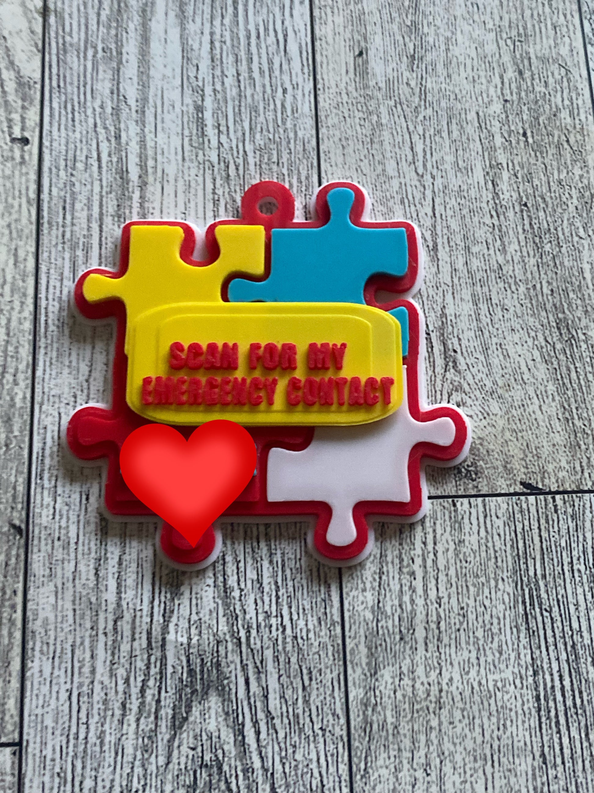 Colorful puzzle piece with a heart and tap for emergency contact text on a wooden surface