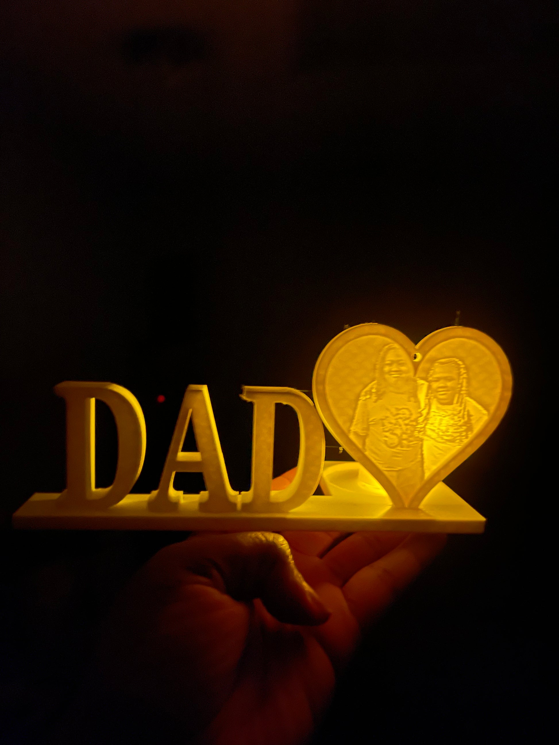 A 3D printed personalized DAD lithophane light display with a glowing heart, spelling out the word 'DAD' in capital letters.