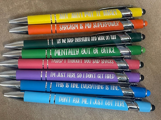 Stack of pens with humorous text on a brown surface