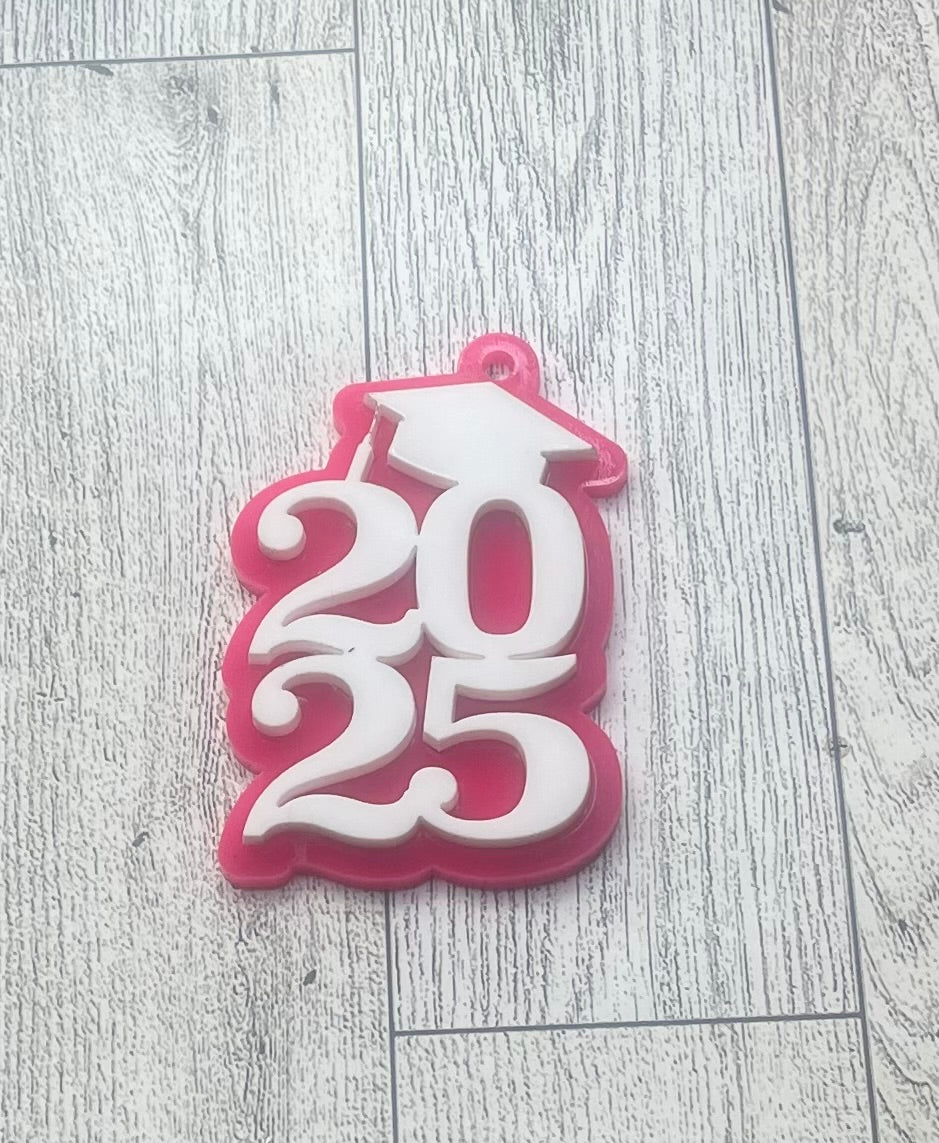 A pink and white acrylic keychain with the numbers 2025 layered on it, representing a senior celebration.