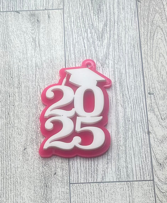 A pink and white acrylic keychain with the numbers 2025 layered on it, representing a senior celebration.