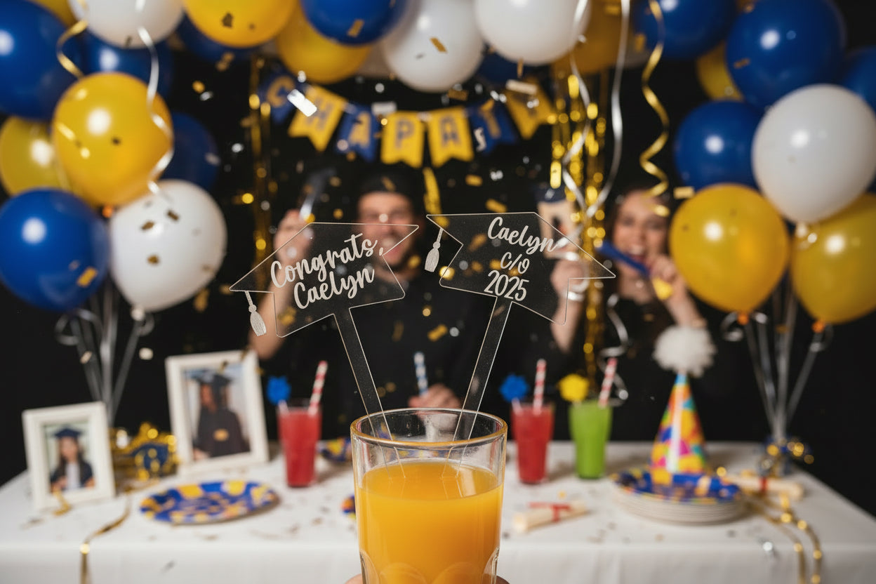 A hand holding two clear acrylic drink stirrers with text on them.