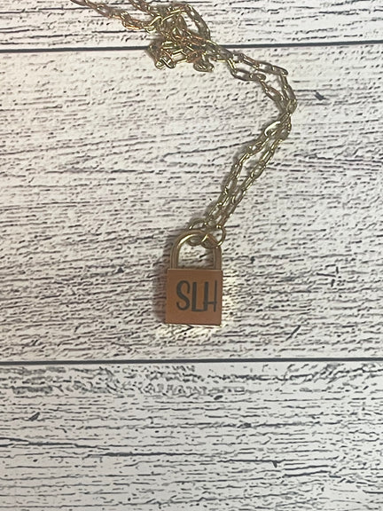 Gold necklace with a lock pendant on a wooden surface