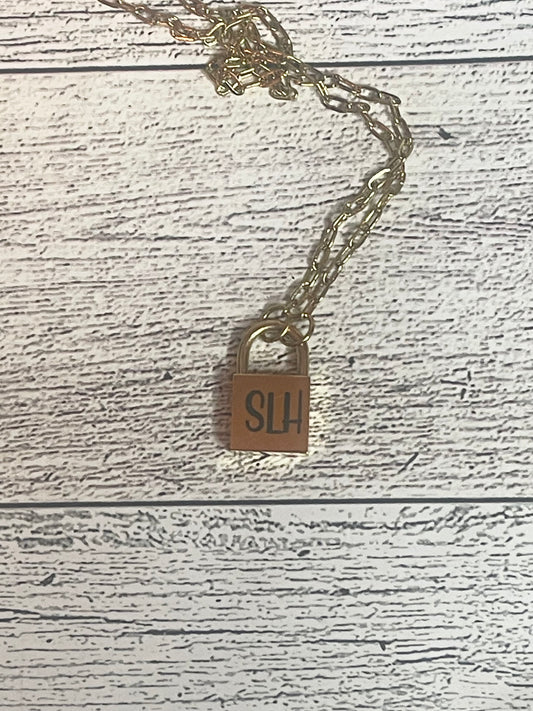 Gold necklace with a lock pendant on a wooden surface