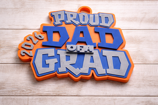 Turnover chain with 'Proud Dad of a Grad' text on a wooden surface