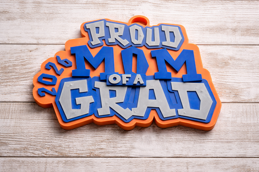 Turnover chain reading 'Proud Mom of a Grad 2026' on a wooden surface
