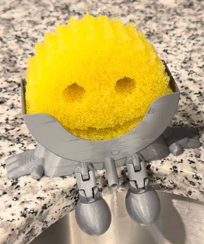 Yellow sponge with a gray holder on a speckled countertop