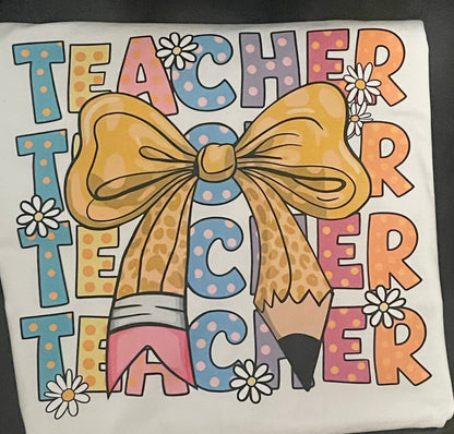 T-shirt with Teacher  text repeated and a bow design on a white shirt.