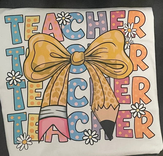 T-shirt with Teacher  text repeated and a bow design on a white shirt.