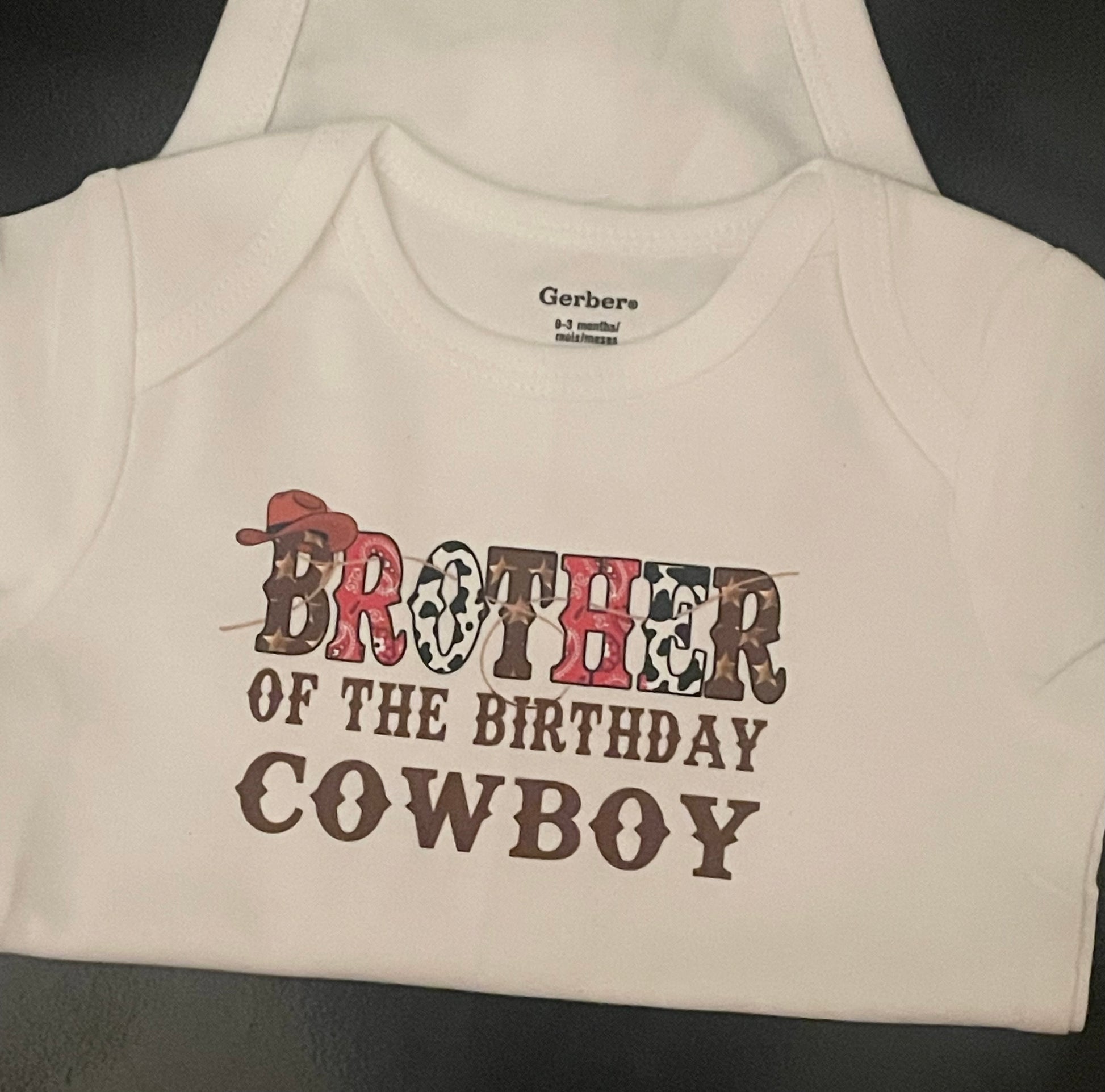 Baby onesie with 'Brother of the Birthday Cowboy' text on a plain background