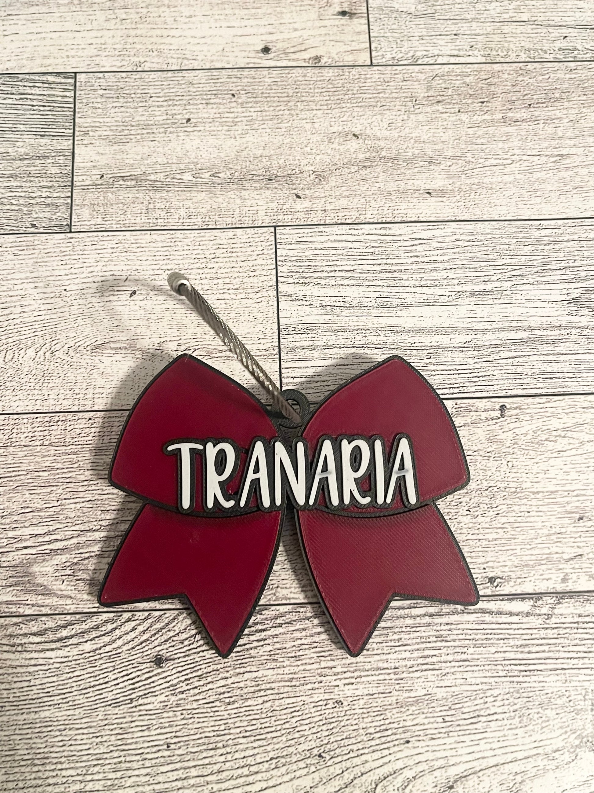 Red bow-shaped sign with name text on a wooden surface