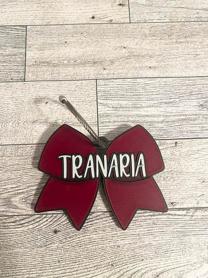 Red bow-shaped sign with name text on a wooden surface