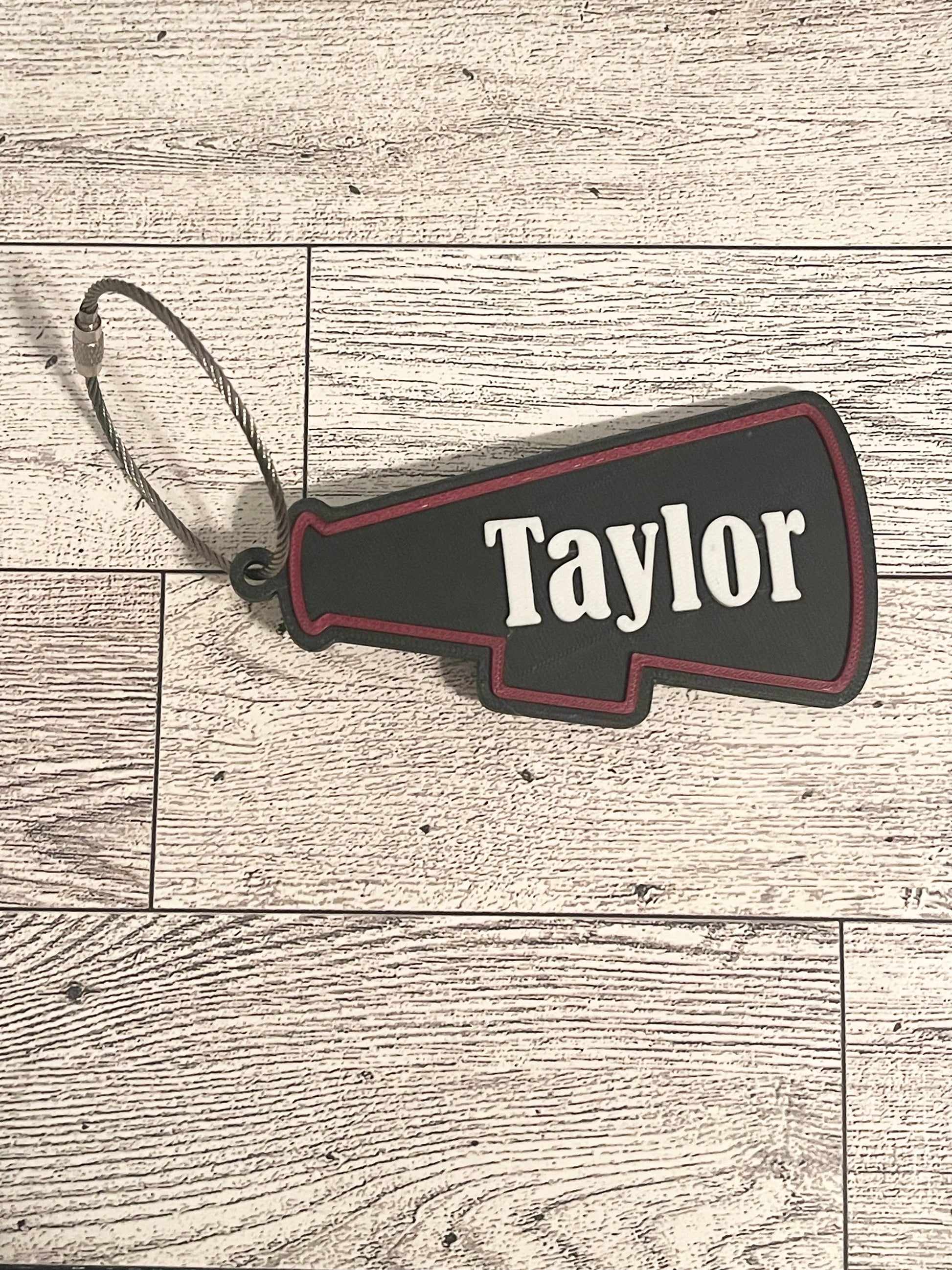 Black and red cheer megaphone backpack tag with text on a wooden surface