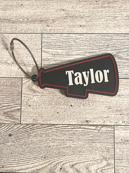 Black and red cheer megaphone backpack tag with text on a wooden surface