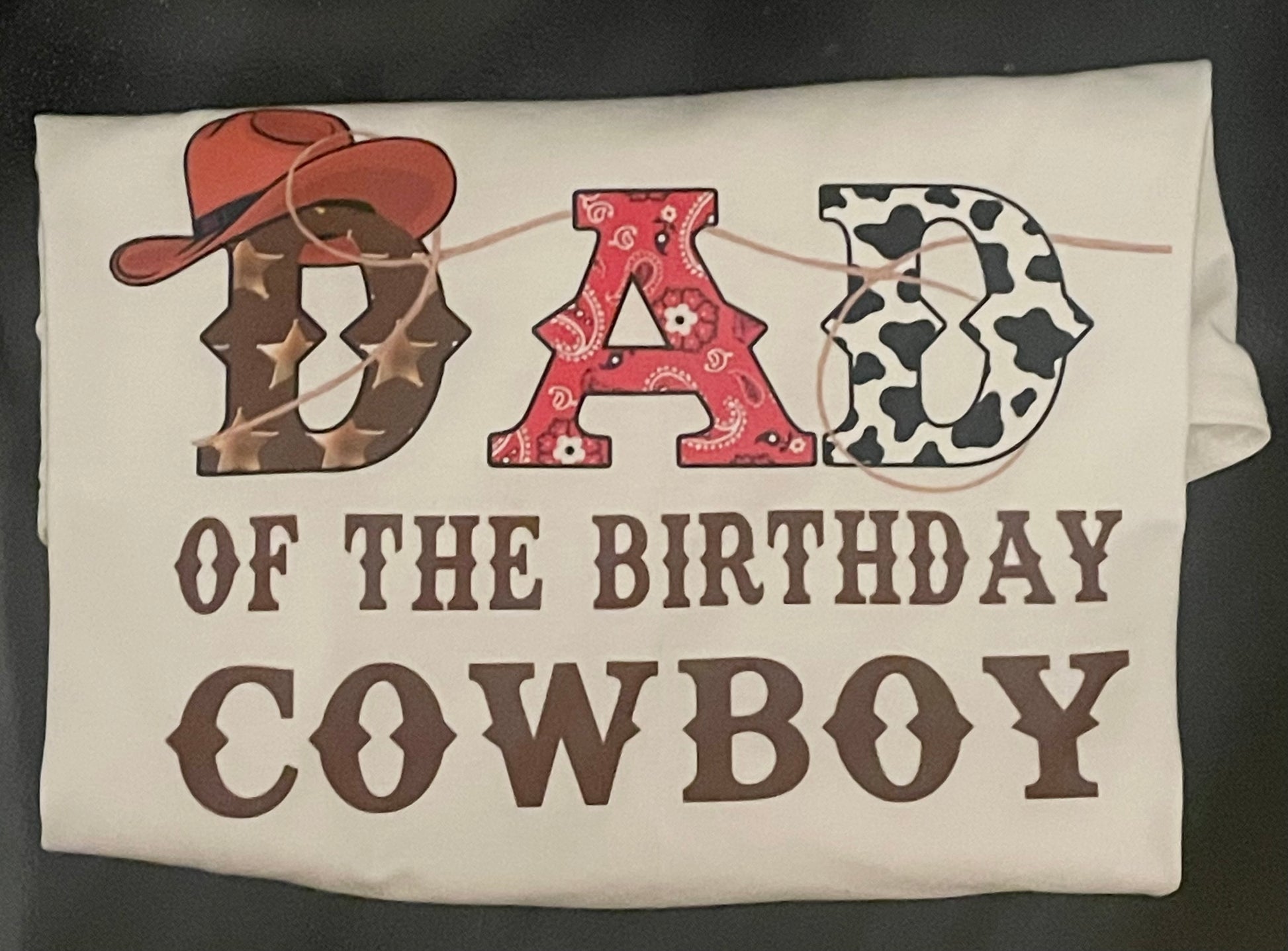 Decorative shirt with cowboy-themed text and graphics on a plain background.