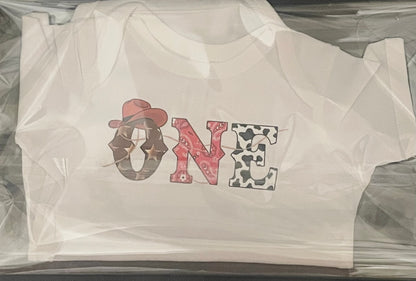 White t-shirt with 'ONE' design in cowboy hat and star pattern.