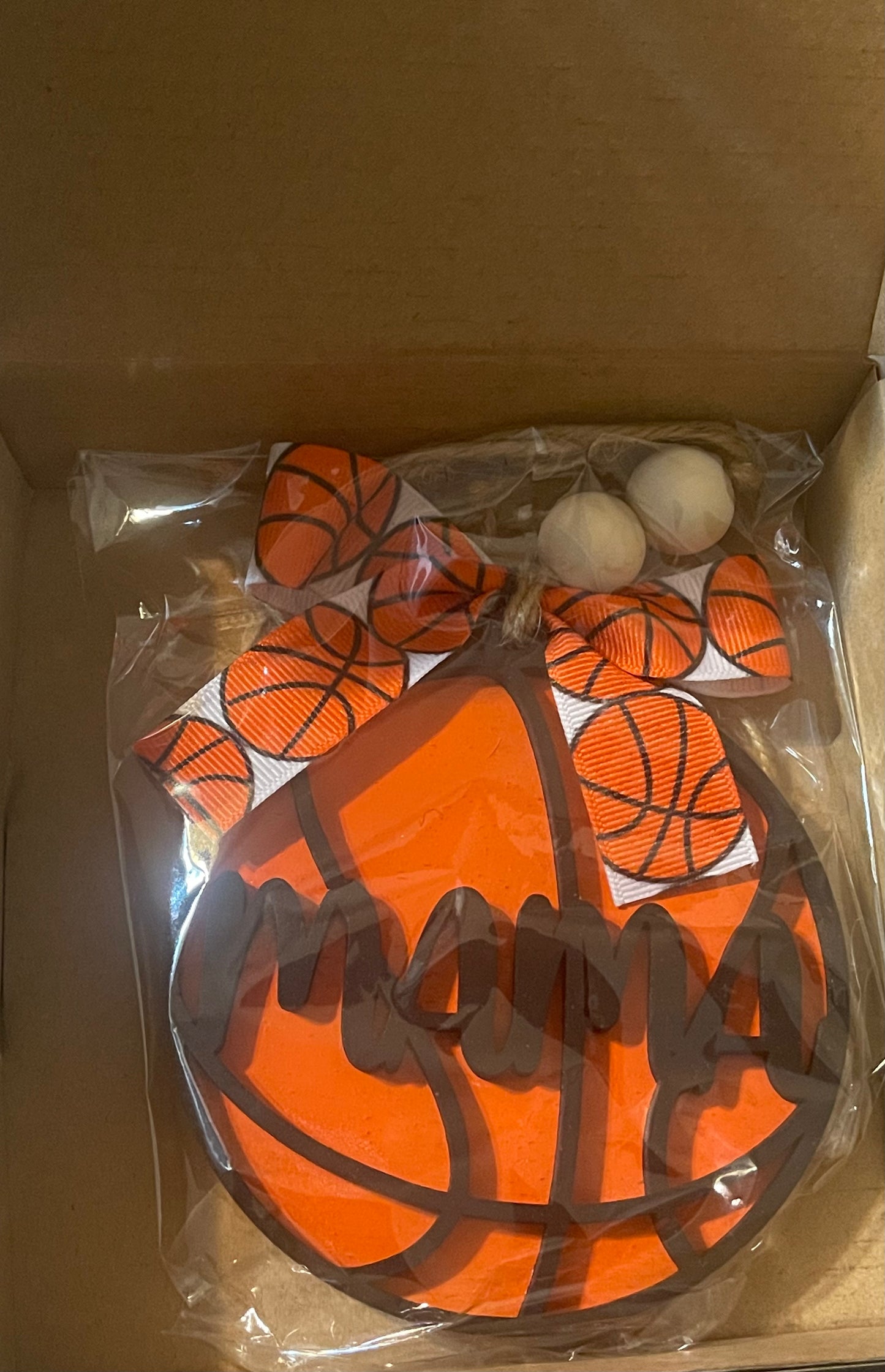 An orange and black basketball-shaped car charm packaged in a clear plastic bag.