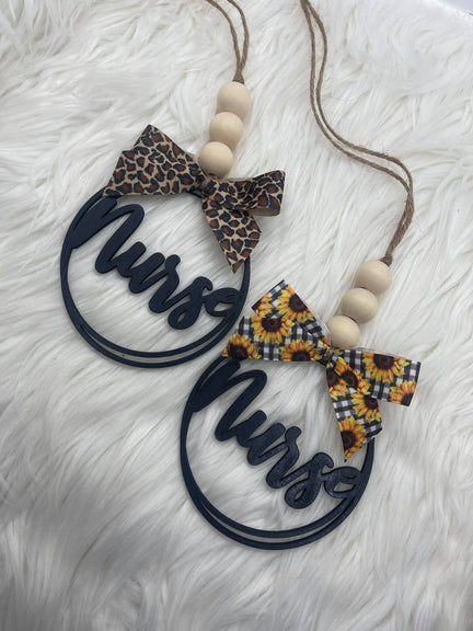 A 'Nurse' car charm featuring a wooden round tag with a bow.