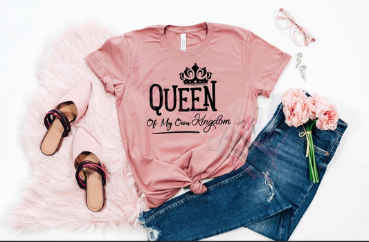 A pink t-shirt with the text 'QUEEN' and 'MY OWN KINGDOM' printed on the front.