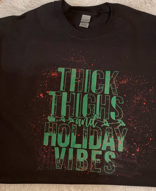Black t-shirt with the text 'THICK THIGHS HOLIDAY VIBES' printed in green on the front.