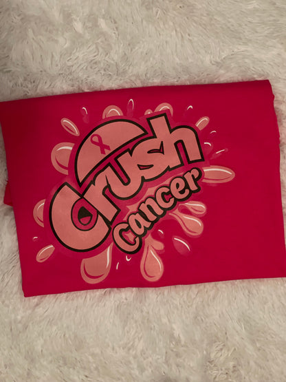 A pink t-shirt with the text 'Crush Cancer' and a graphic design resembling a splash or a fizzy drink.